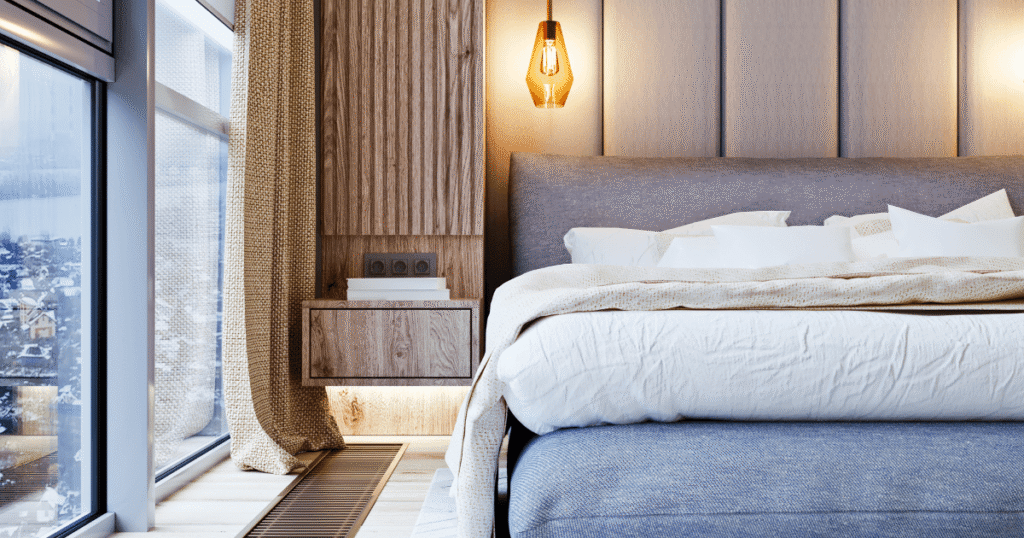 Quarto de casal com uma cabeceira estofada cinza, mostrando como escolher a cabeceira de cama ideal.